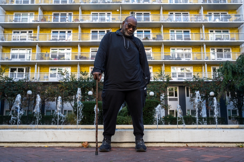 fotografia de fred moten em pé em frente a um prédio amarelo